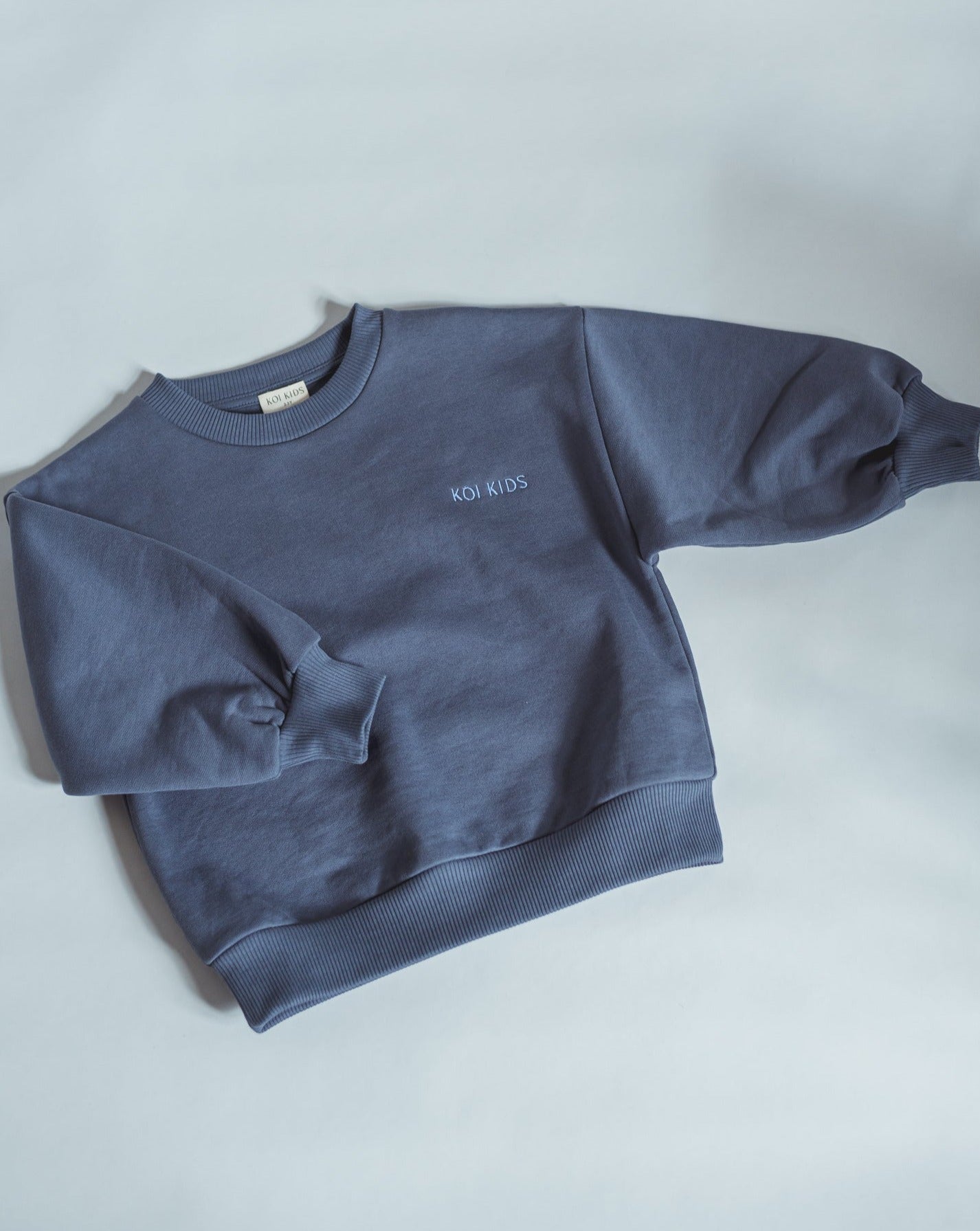 Denim blue sweatshirt with light blue logo embroidery, dropped shoulders and foldable cuffs with an oversized fit.